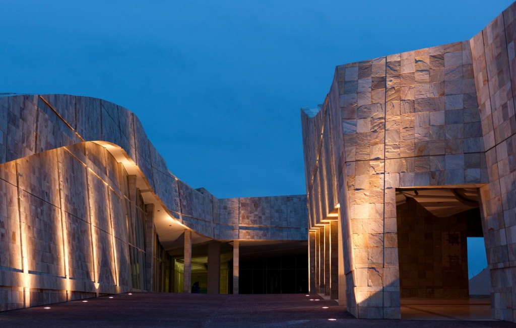 Detalle arquitectónico de la Ciudad de la Cultura de Galicia al atardecer, iluminación cálida en muros de piedra