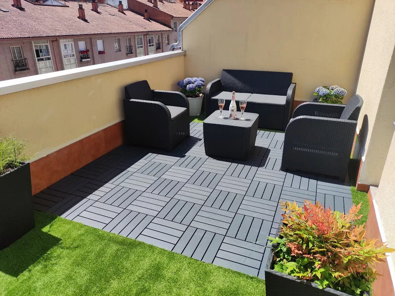 Terraza privada con césped artificial, zona de estar y copas de vino en apartamento turístico en Galicia
