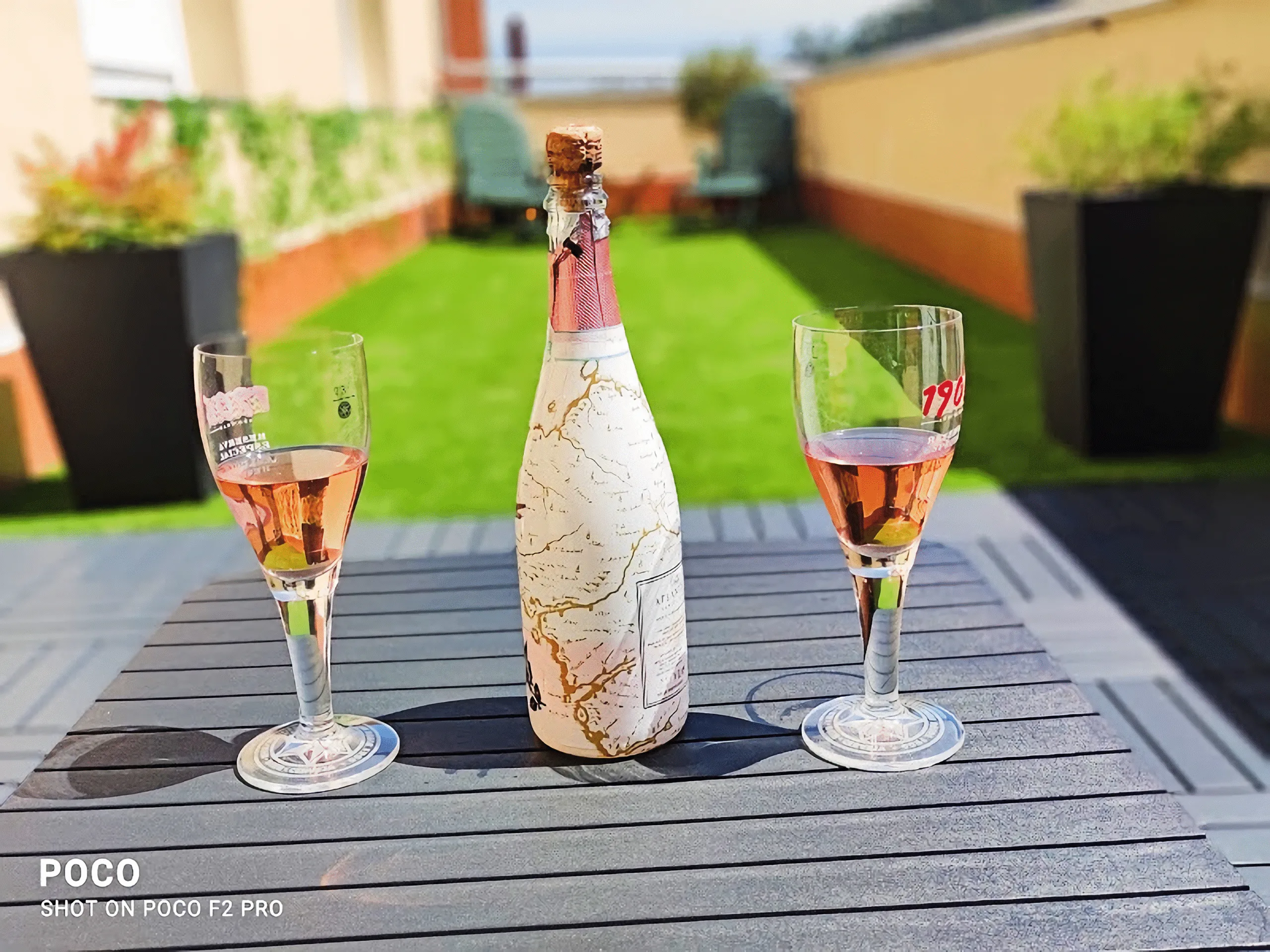 Botella de vino rosado y dos copas en mesa al aire libre en la terraza del apartamento turístico en Galicia