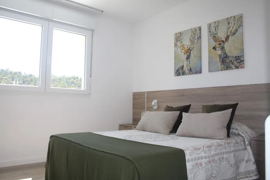 Dormitorio luminoso con cama doble, decoración natural y vistas al bosque en alojamiento cerca de Santiago