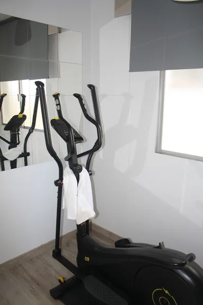 Zona de ejercicio con bicicleta elíptica y espejo en apartamento turístico en Galicia
