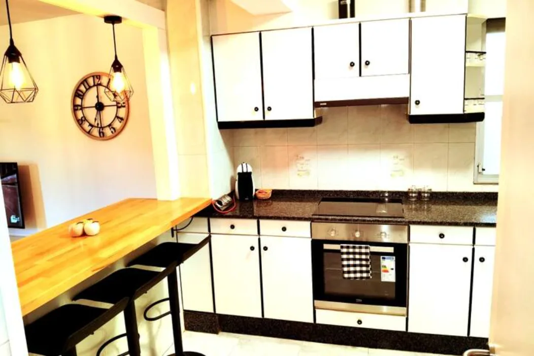 Cocina equipada con barra americana, horno, cafetera y diseño vintage en apartamento turístico en Galicia