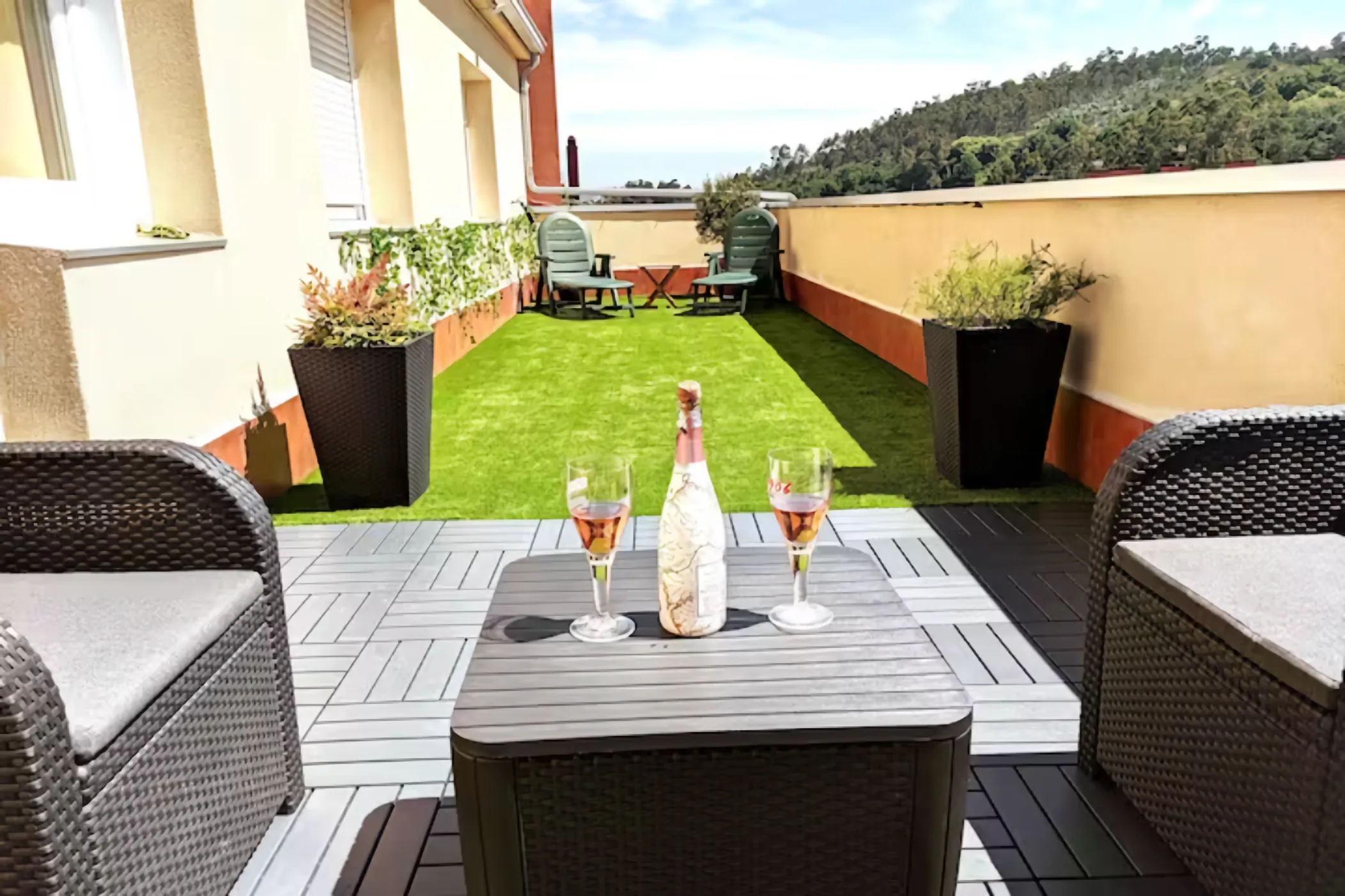 Terraza privada con césped artificial, cava y copas en apartamento turístico cerca de Santiago